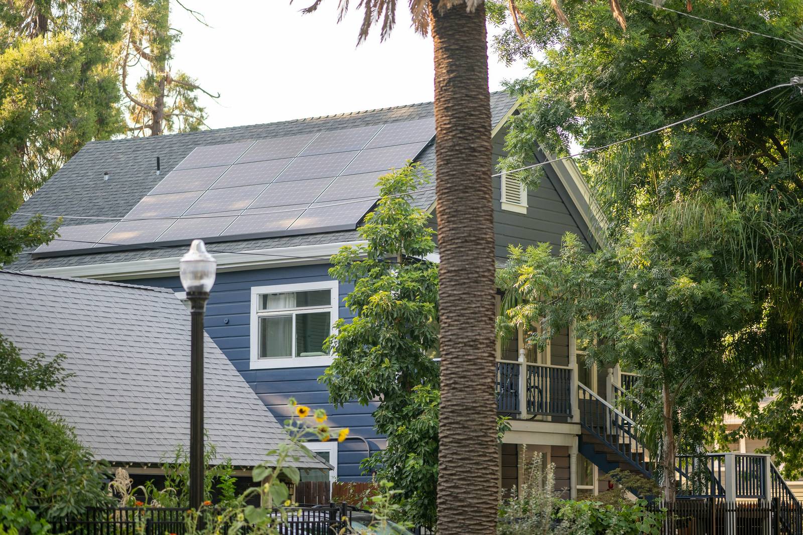 Sunlit two-story rental home with rooftop solar panels in warm morning light